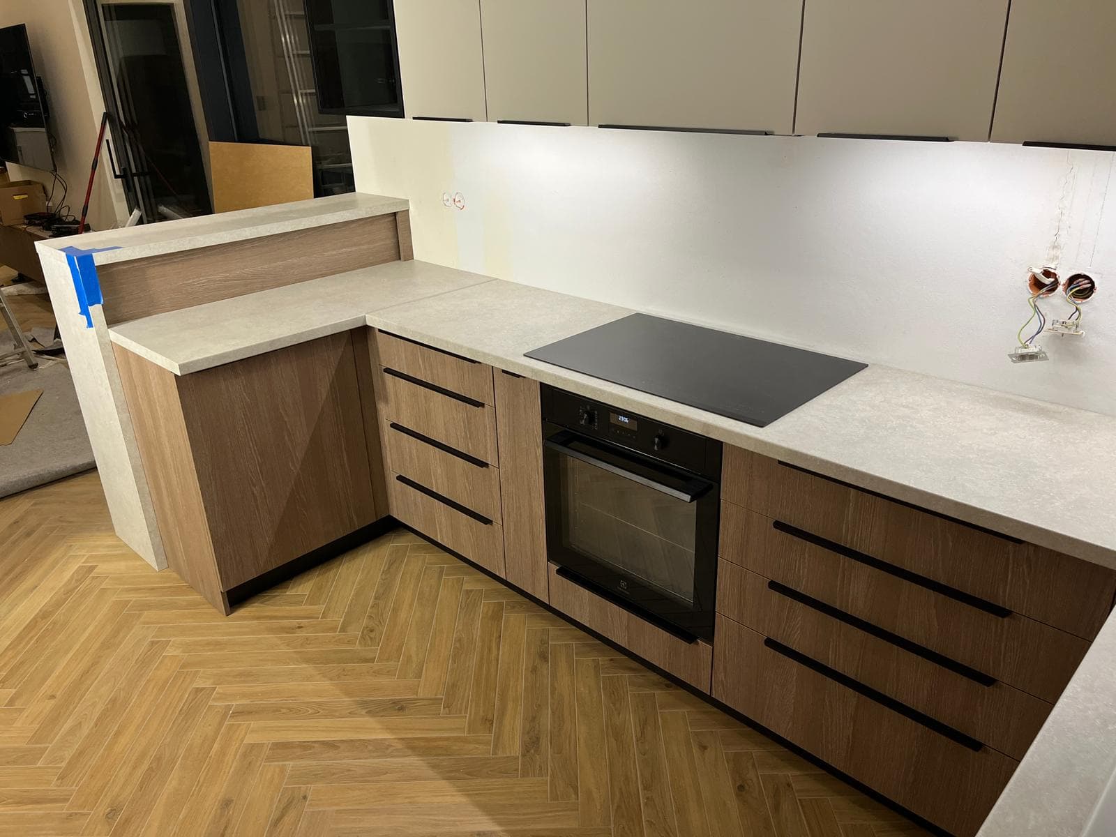 Kuchnia z dębowymi dolnymi frontami, beżową górą i półwyspem z blatem kamiennym
