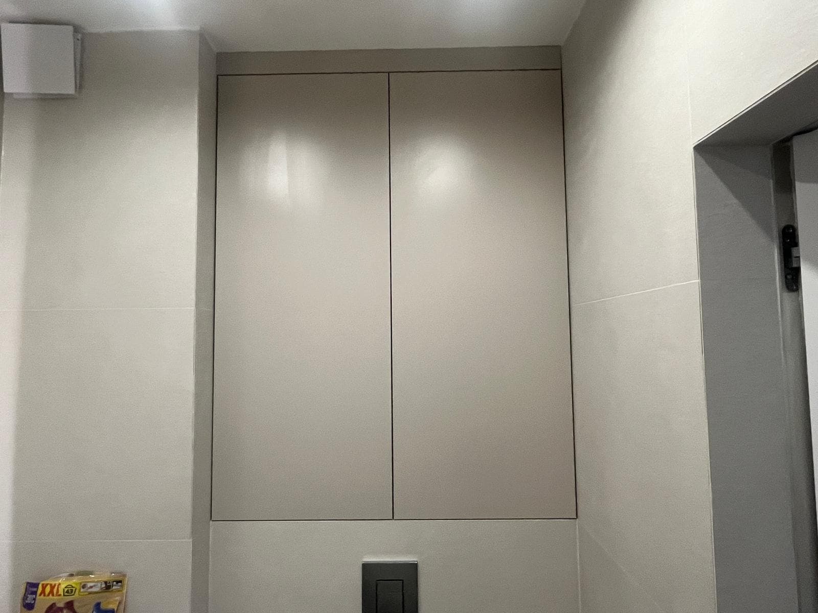 Zabudowa nad WC z gładkimi frontami wtopiona w ścianę łazienki