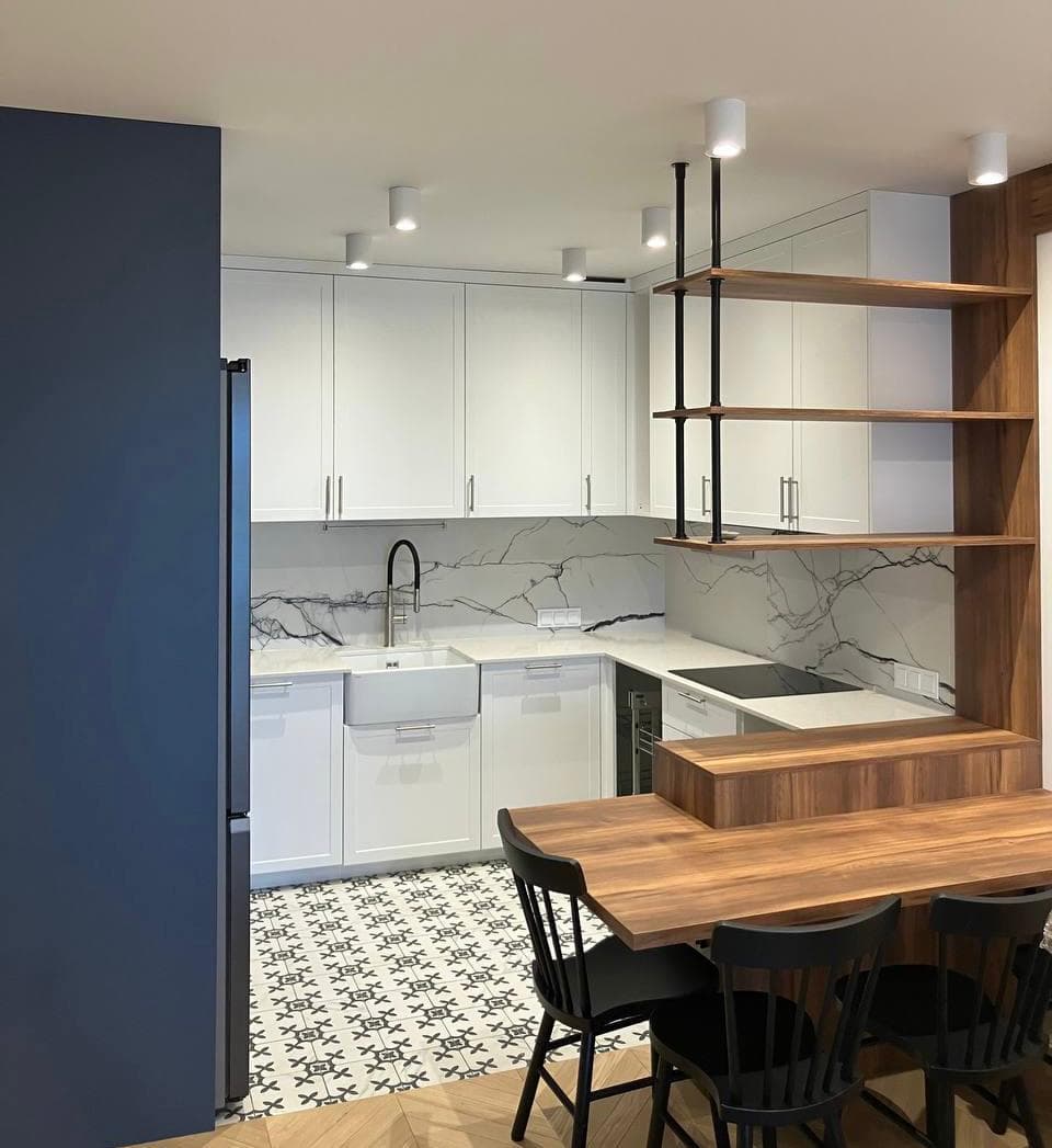 Biała kuchnia z marmurowym backsplash, drewnianym barem, wzorzystą podłogą i niebieską lodówką